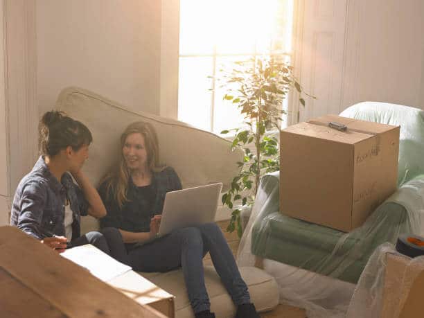 Deux jeunes colocataires qui déménagent dans leur nouvel appartement rempli de cartons